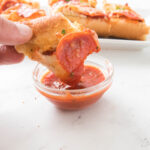 dipping garlic bread pizza in pizza sauce