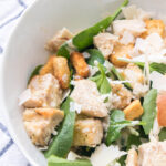 close up vertical shot of chicken Caesar salad in a white bowl