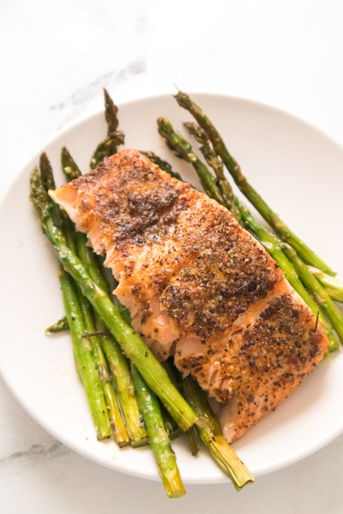 vertical overhead shot of salmon and asparagus on white plate